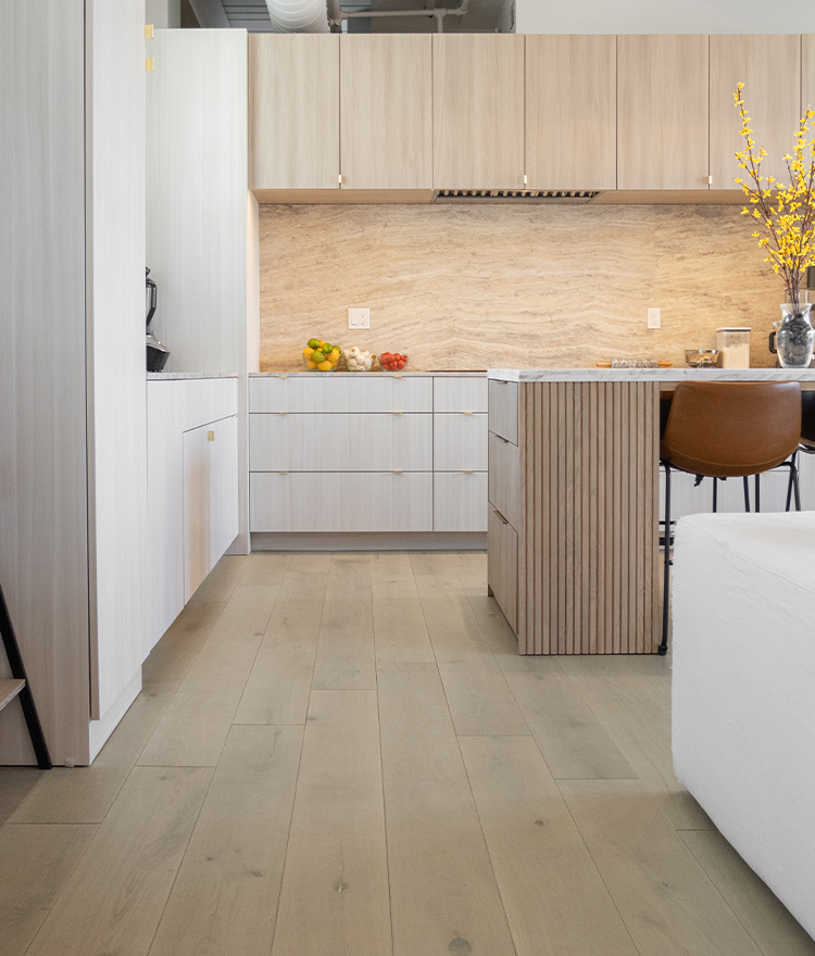 Modern, minimalist kitchen design with wide-plank wood flooring. Cabinets with light wood tones and sleek cabinets.