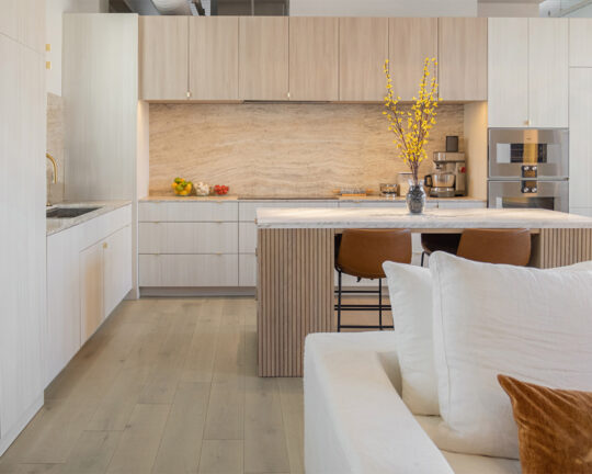 Modern kitchen with lightly colored interior design and light brown wood flooring