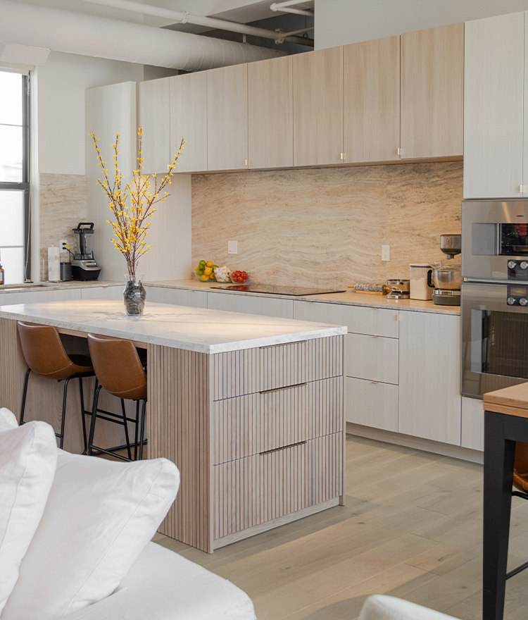 Modern penthouse kitchen with light cabinets, decorative plant, and light wood floor