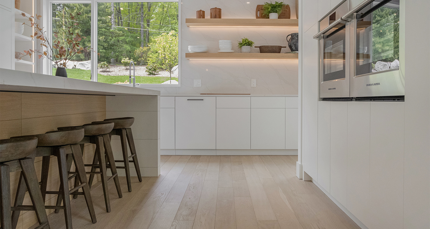 Kitchen and island with white walls and cabinets with oak wood flooring.
