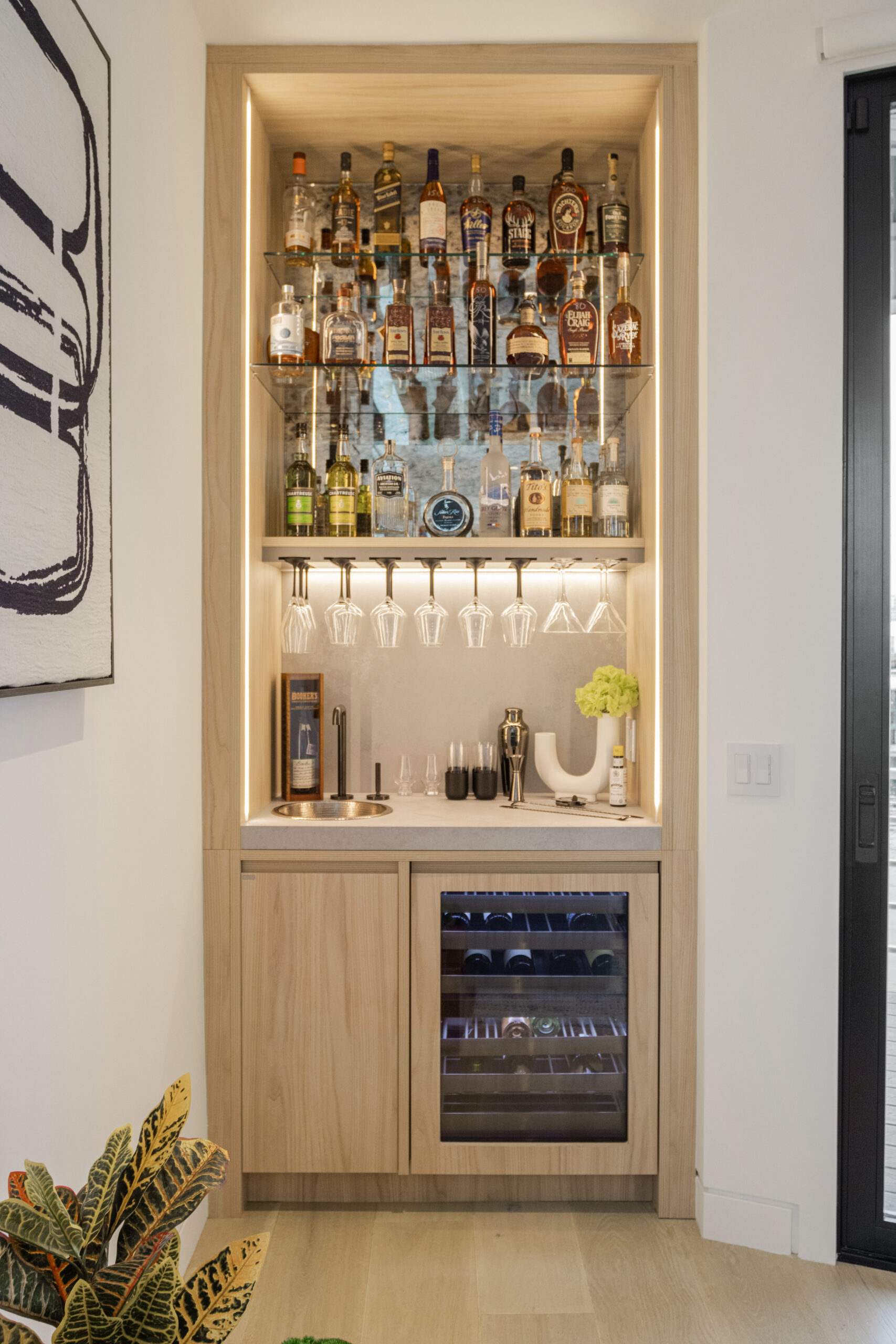 lit up wet bar with wooden accents and light wide plank flooring