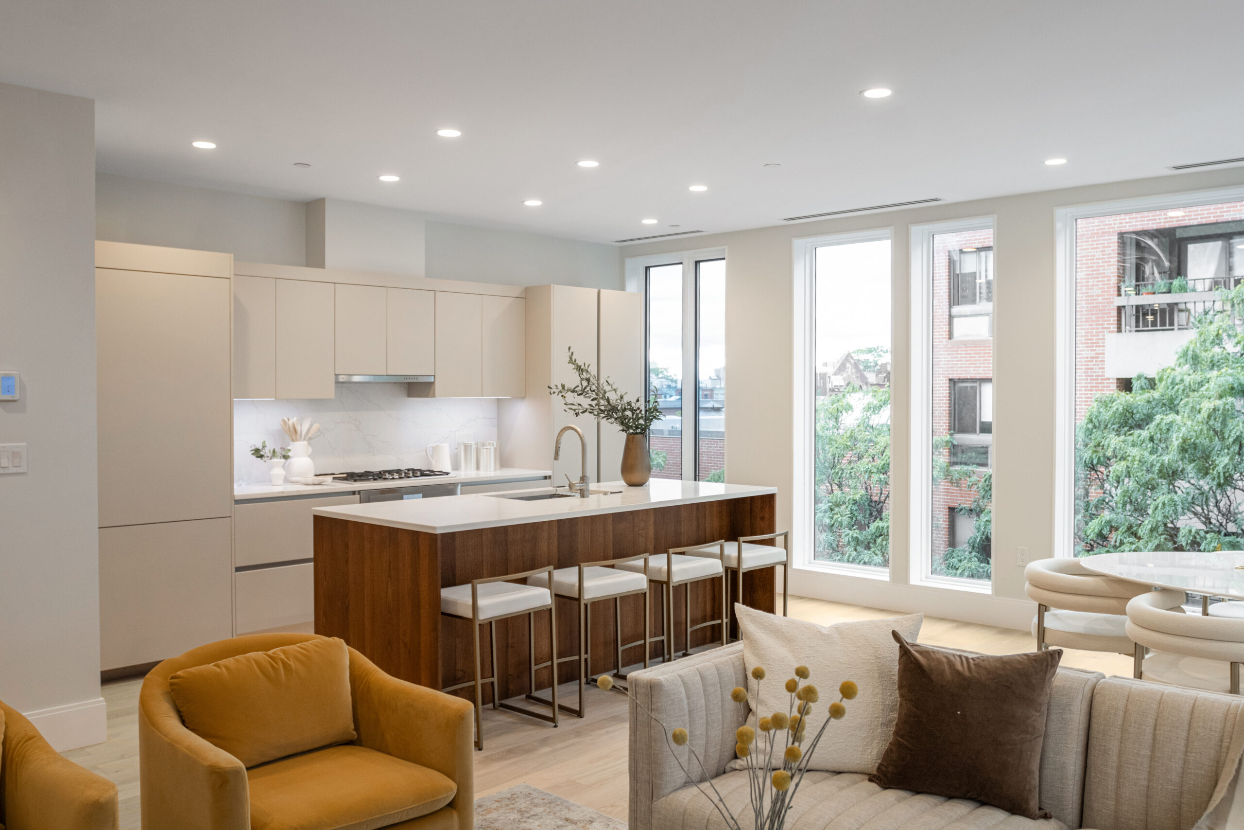 open living and kitchen place with floor to ceiling windows neutral furniture and cabinets and walls and light wide plank flooring
