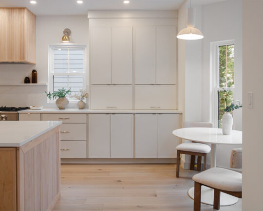 modern kitchen with off white cabinets and a wooden island with wide plank floors