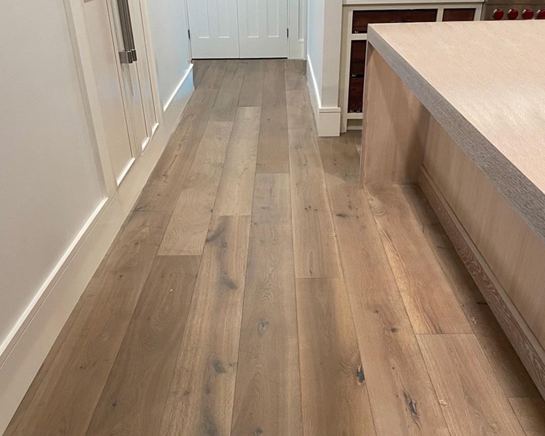 Natural brown wide plank flooring with character in a white kitchen