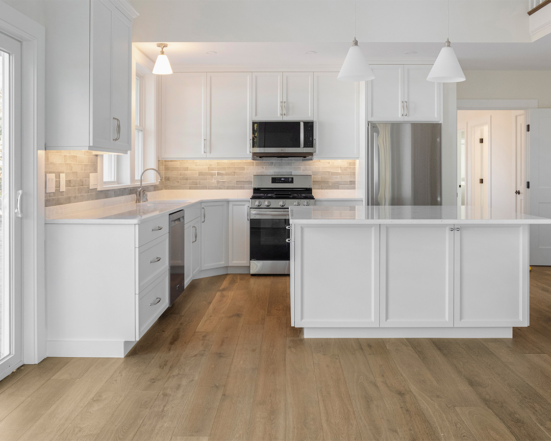 white kitchen with wide plank brown flooring